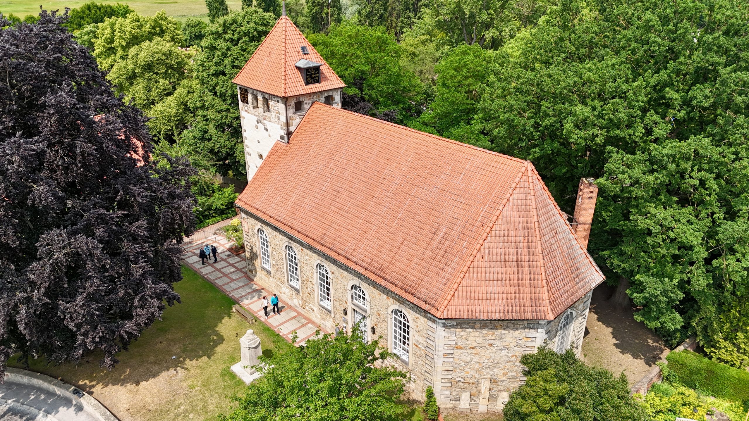 Luftaufnahme der St. Marien-Kirche in Laatzen-Grasdorf mit rotem Ziegeldach, umgeben von Bäumen – Standort des Kolumbariums Grasdorf für Urnenbeisetzungen.