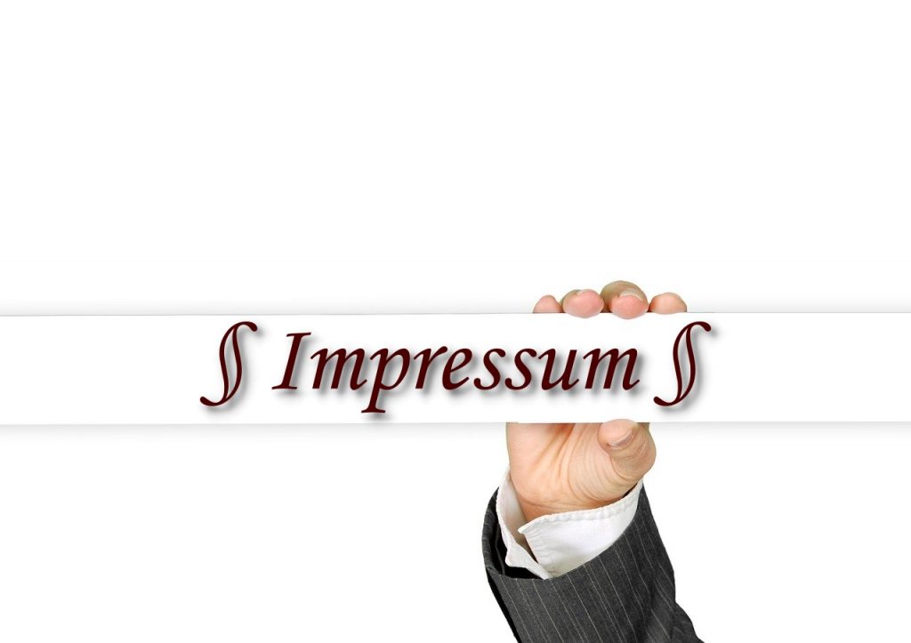 Hand hält Schild mit der Aufschrift Impressum – Symbolbild für rechtliche Informationen von Löer Bestattungen in Laatzen