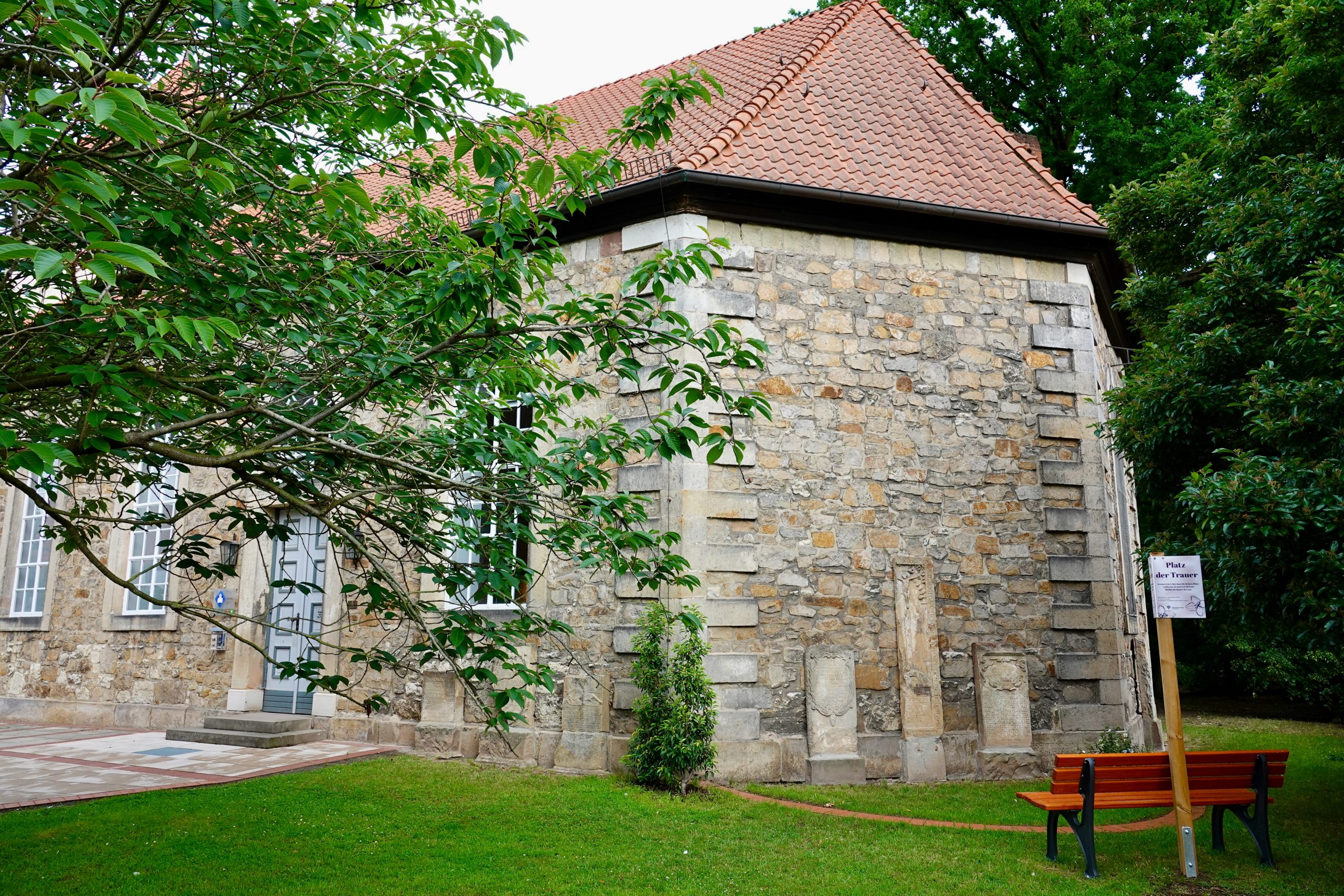 Platz der Trauer an der St.-Marien-Kirche in Grasdorf mit Sitzbank und alten Kirchenmauern