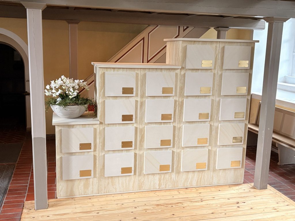 Urnenwand aus Sandstein im Kolumbarium Laatzen-Grasdorf mit Blumenschmuck