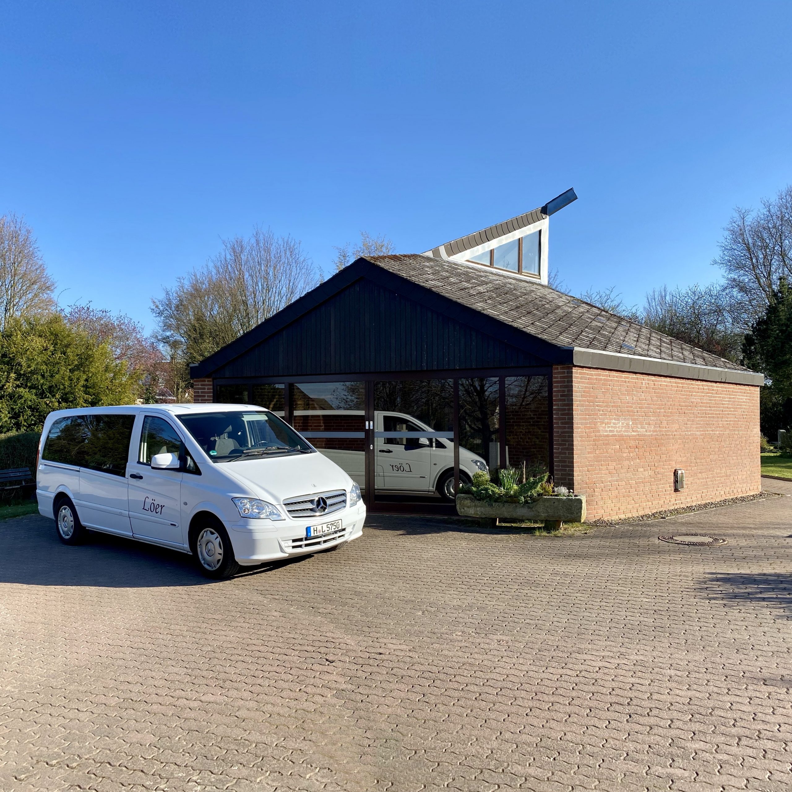 Weißer Bestattungswagen von Löer Bestattungen vor der Kapelle des Friedhofs Oesselse in Laatzen