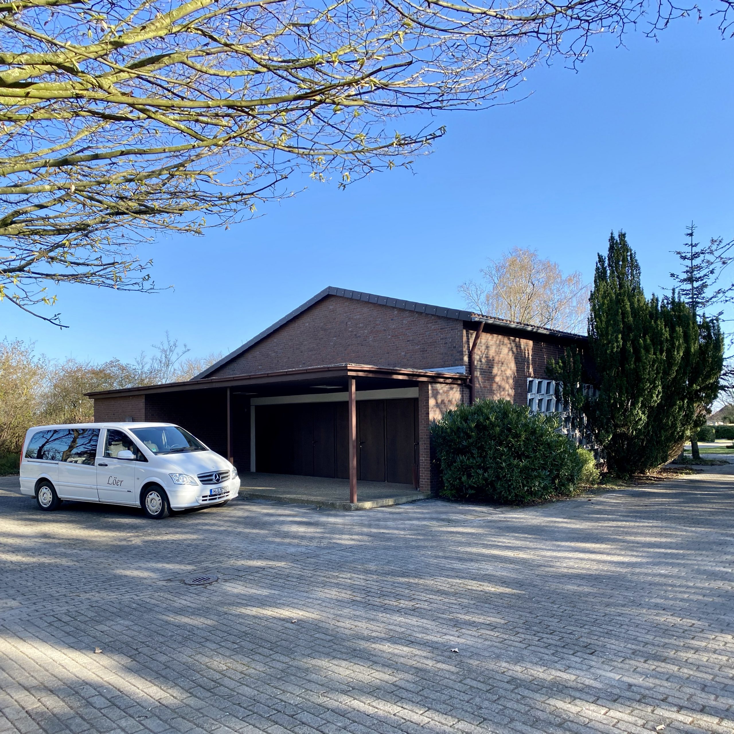 Weißer Bestattungswagen von Löer Bestattungen vor der Kapelle auf dem Friedhof Rethen in Laatzen